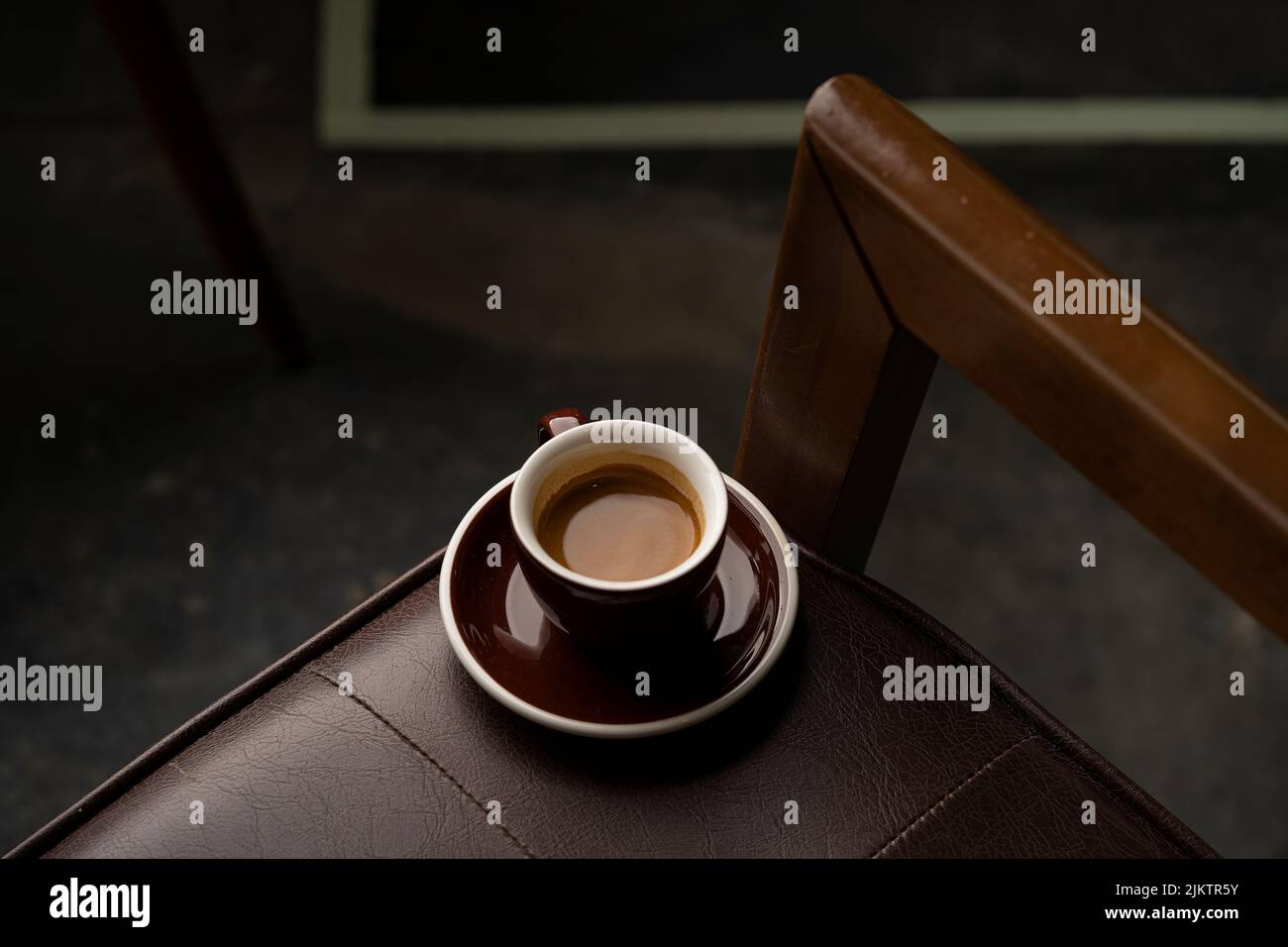 Ein Blick von oben auf eine Tasse Espresso-Kaffee auf einem Ledersessel Stockfoto