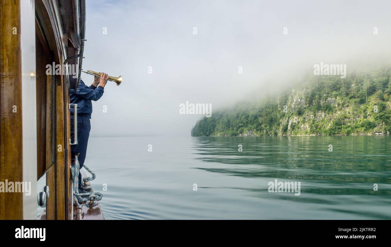 Ein Trompetenspieler an der Echowand am Königssee Stockfoto