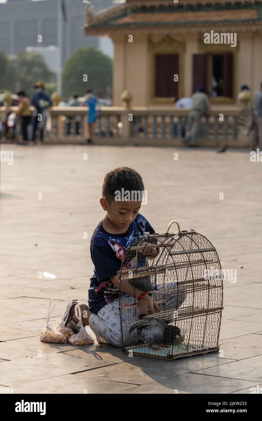 Ein Kind, das mit Wunschvögeln spielt, in Käfigen in der Nähe von Schreinen gehalten, ein Ritual, das „Auflösen“ genannt wird Stockfoto
