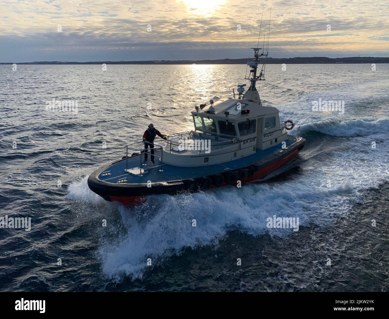 Ein Lotsenboot, das sich einem großen Schiff im Meer nähert Stockfoto