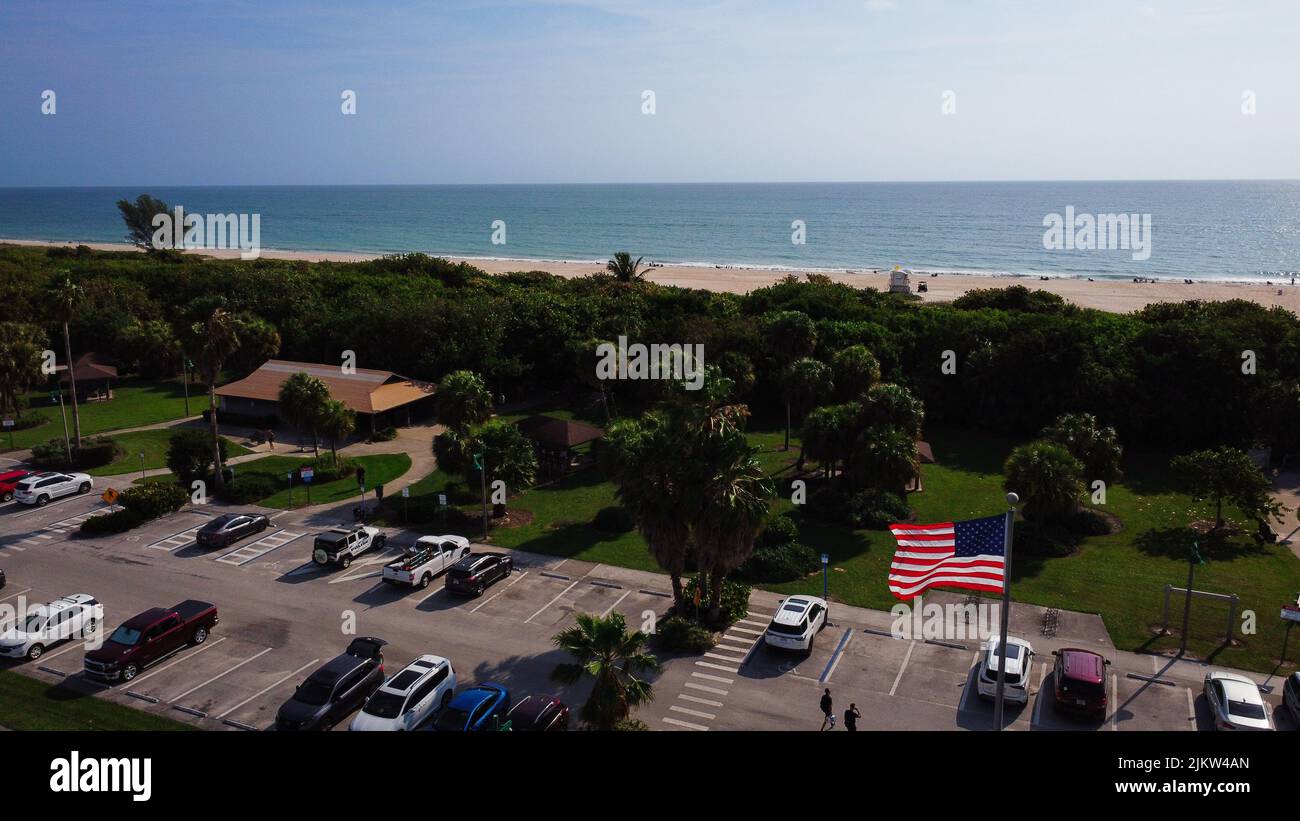 Luftaufnahme eines Ozeans mit geparkten Autos und amerikanischer Flagge auf dem Fahnenmast im Vordergrund Stockfoto