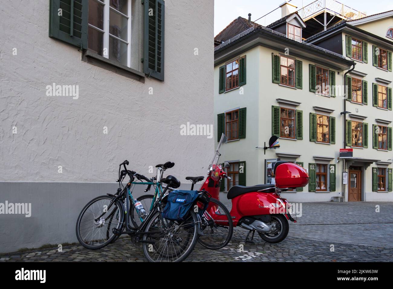 Ein blaues Fahrrad und ein rotes Moped auf der Straße von St. Gallen, Schweiz Stockfoto