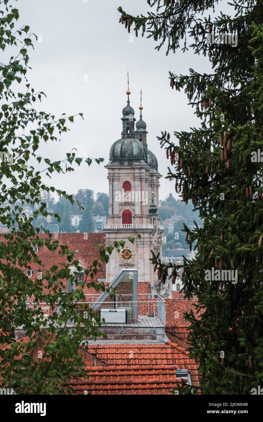 Eine vertikale Aufnahme der Abtei von saint Gall Türme und Ziegeldächer mit Bäumen im Vordergrund Stockfoto