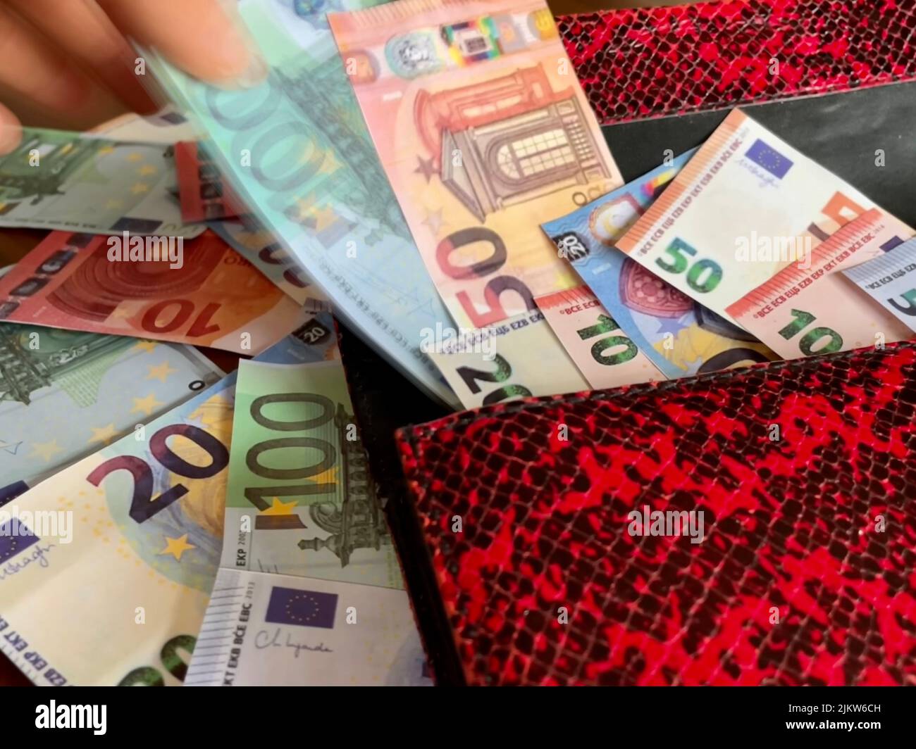 Eine Nahaufnahme einer Hand, die Euro aus der Tasche zieht und mehr Euro auf dem Tisch hat Stockfoto