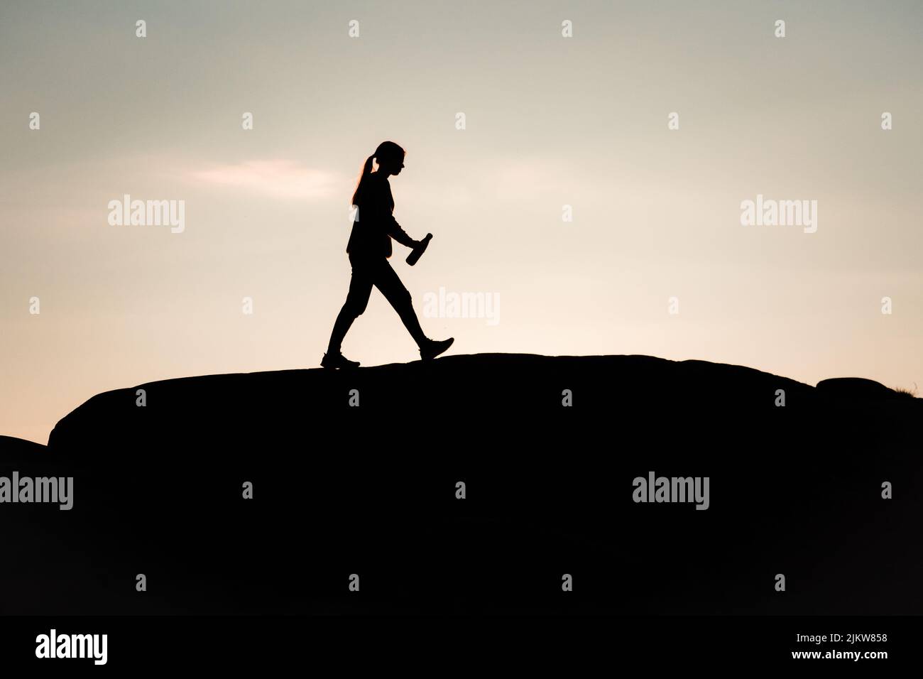 Person, die während des Sonnenuntergangs auf einem Felsen in Silhuette läuft Stockfoto
