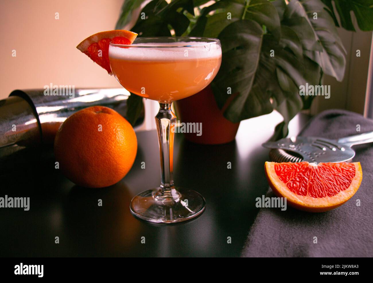 Nahaufnahme eines Grapefruit-Cocktails aus Coupé-Glas mit weißem Schaumstoff auf einem schwarzen Tisch Stockfoto