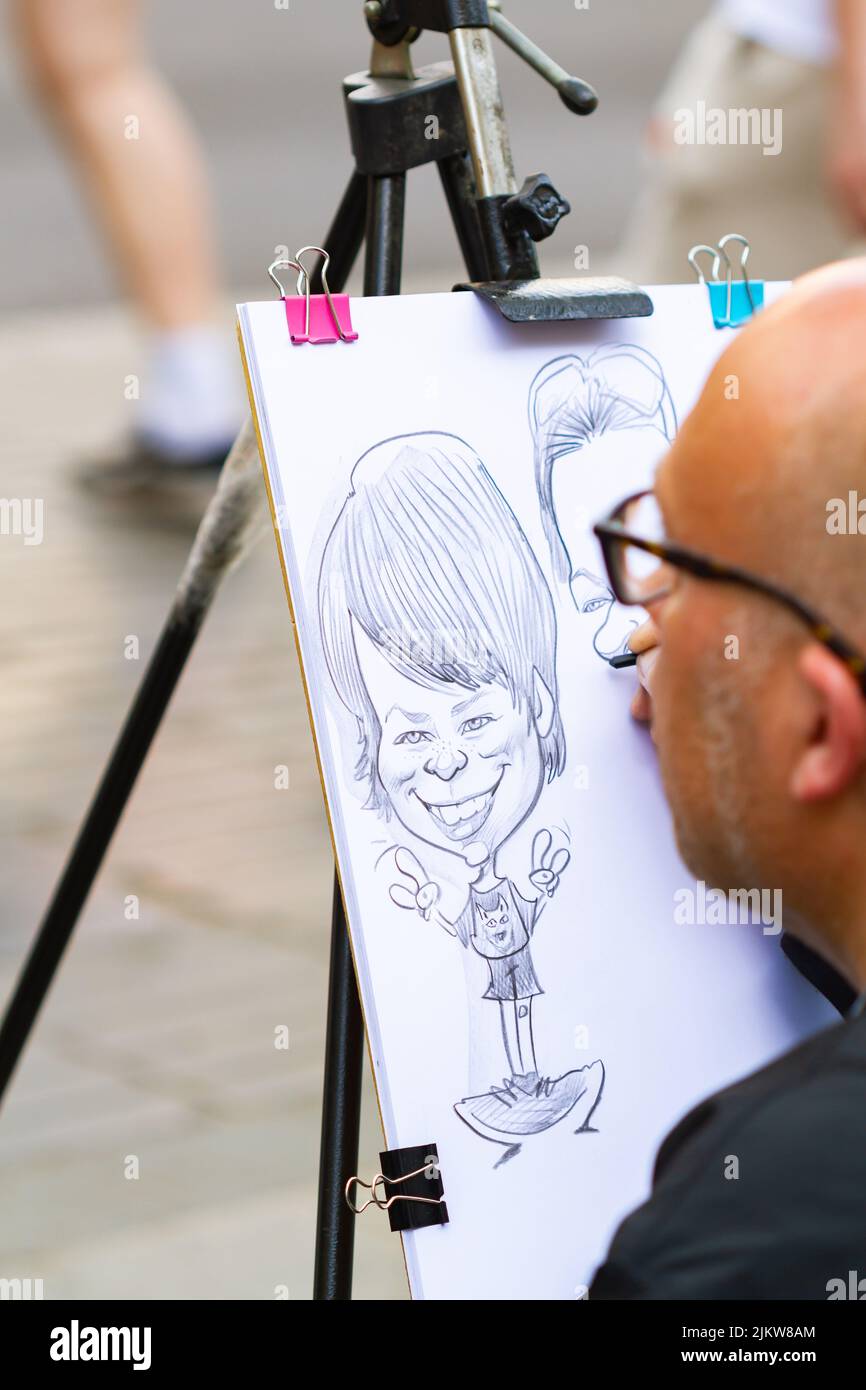 BARCELONA, SPANIEN - 8. APRIL 2022: Straßenkünstler zeichnet auf der ramblas von Barcelona (Spanien) eine Karikatur auf einen Karton, selektiver Ansatz zum Zeichnen Stockfoto