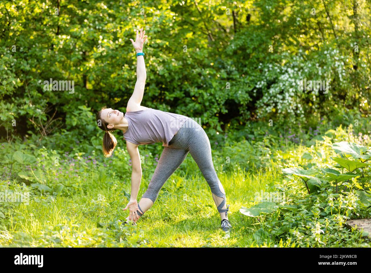Junge Frau macht Dehnübungen in der Natur Stockfoto