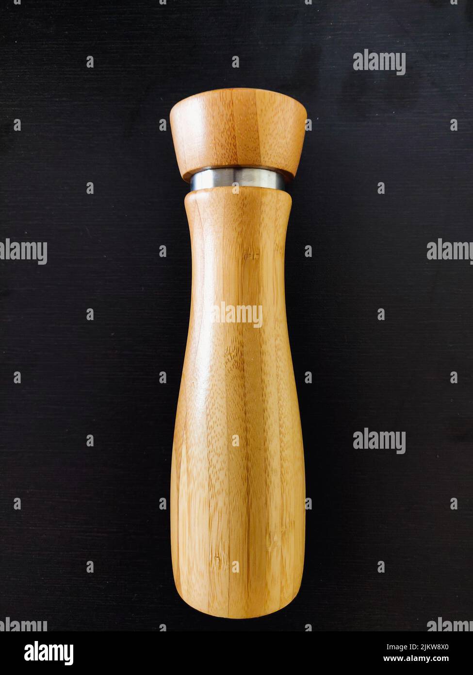 Eine braune Salz-Pfeffermühle aus Holz, isoliert auf schwarzem Hintergrund Stockfoto