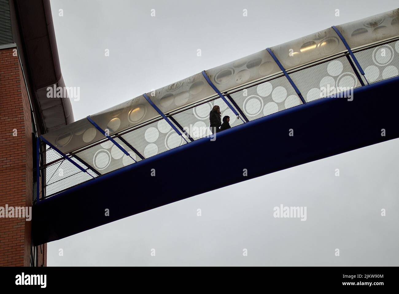 Eine Aufnahme von Menschen, die auf einer geschlossenen Fußgängerbrücke spazieren, die einen Parkplatz mit dem Bullring-Einkaufszentrum in Birmingham, Großbritannien, verbindet Stockfoto