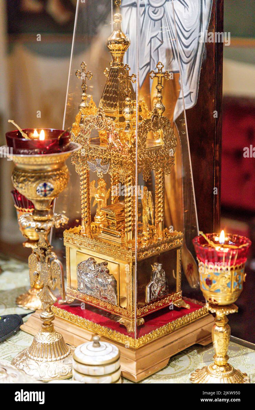 Eine vertikale Nahaufnahme einer goldenen Schreinminiatur und zündete Ölkerzen auf dem Altar der östlichen orthodoxen Kirche an Stockfoto