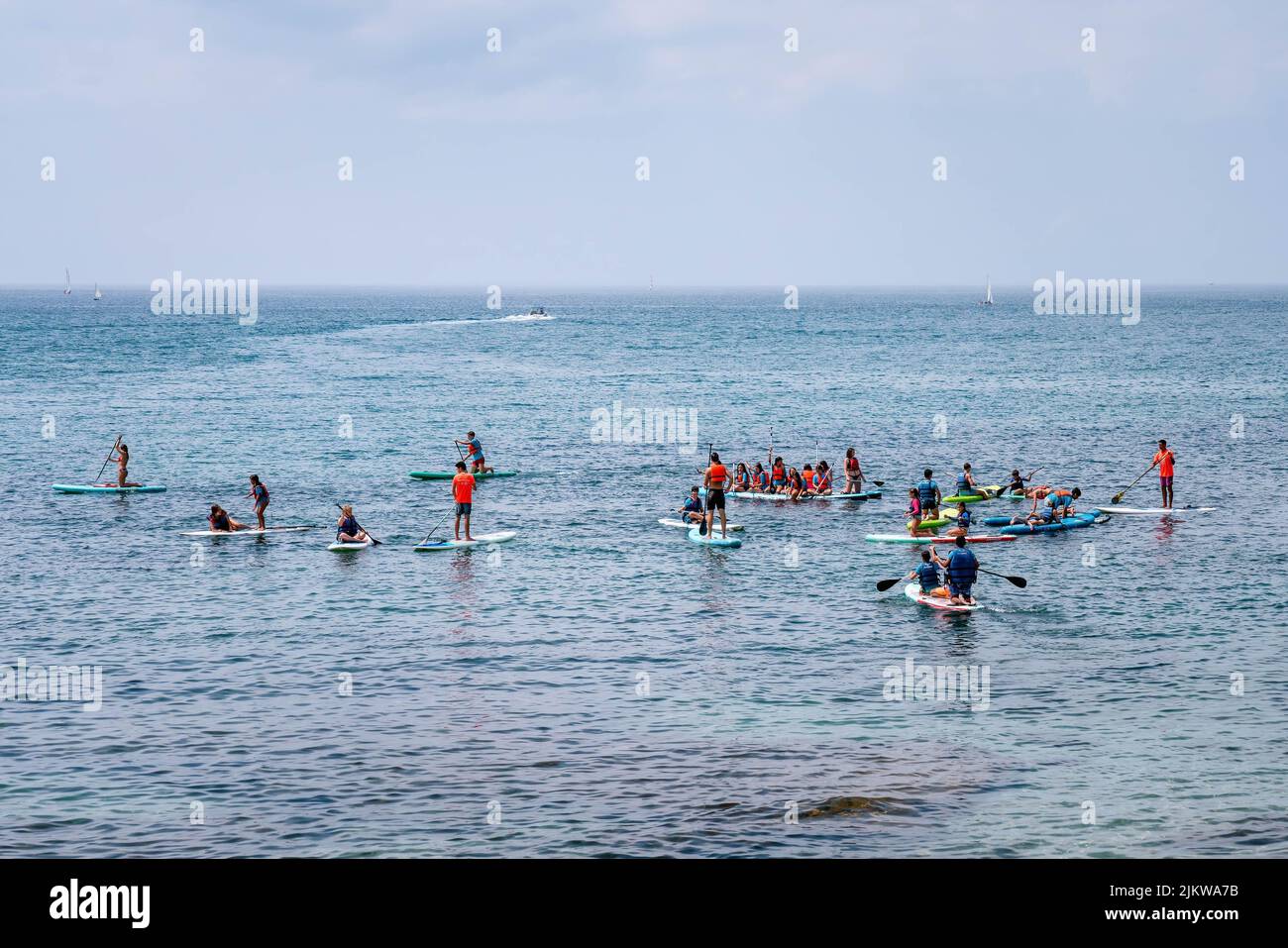 Stand Up Paddling Training Aktivität - Gruppe von Teenagern mit wenigen Erwachsenen trainieren im offenen Meerwasser, MARBELLA, MALAGA/SPANIEN - JULI 21 2022 Stockfoto