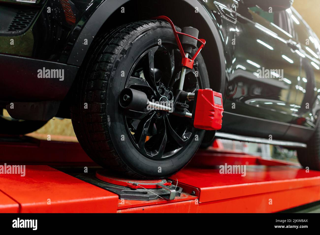 Kfz-Mechaniker, der Radausrichtungssensoren installiert und die Autoaufhängung eingestellt hat. Automechaniker bei der Arbeit Stockfoto