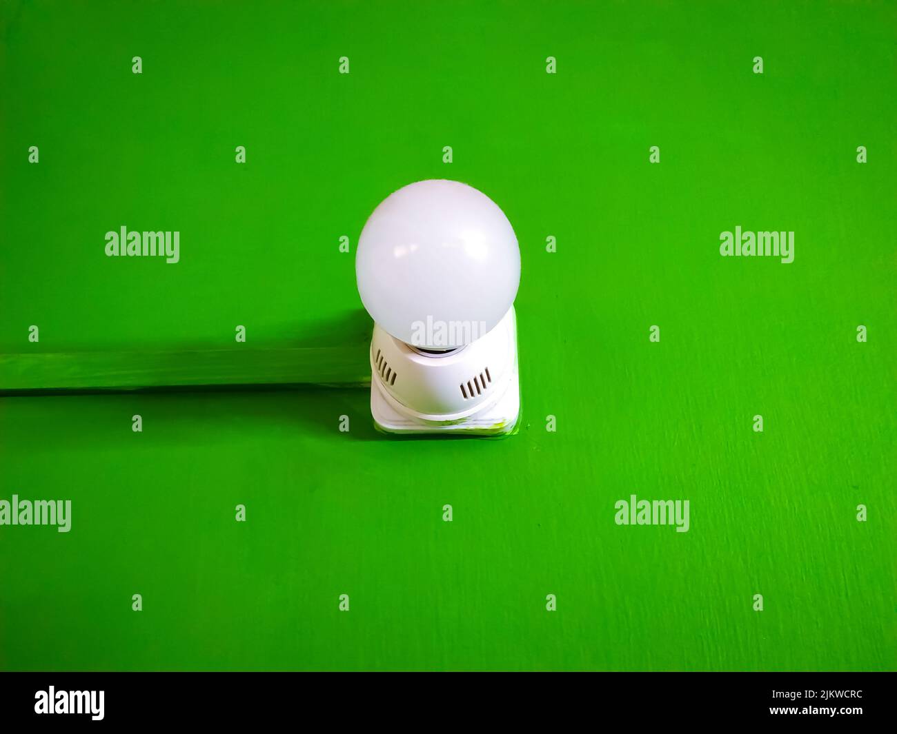 Nahaufnahme einer Glühbirne mit einem weißen Lampenhalter aus Kunststoff, isoliert auf einem grünen Chroma-Hintergrund Stockfoto