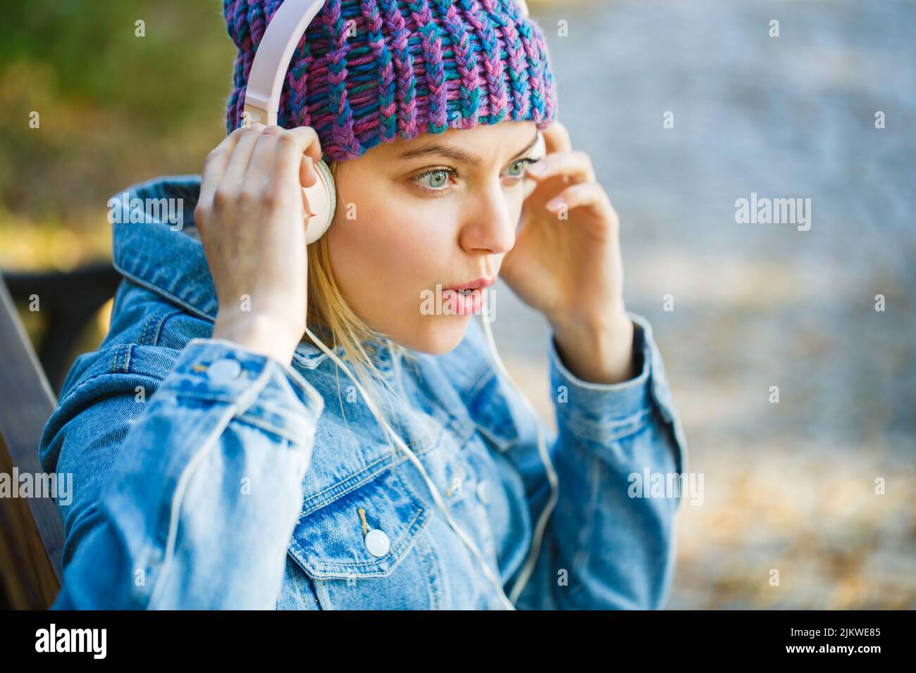 Lächelndes Mädchen entspannt, Musik ein Smartphone und Kopfhörer. Im Freien Porträt eines trendigen Mädchen. Herbstmelodie-Konzept. Herbst gemütliche Atmosphäre. Frau mit Stockfoto