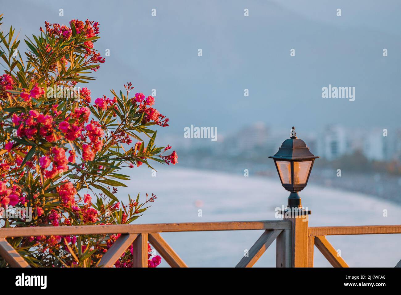 Berühmter Strand von Konyaalti, landschaftlich reizvoller Blick auf die Stadt von einem Aussichtspunkt aus. Dekorative Laterne und Holzzaun und blühende Blumen im Frühling. Reisedesti Stockfoto
