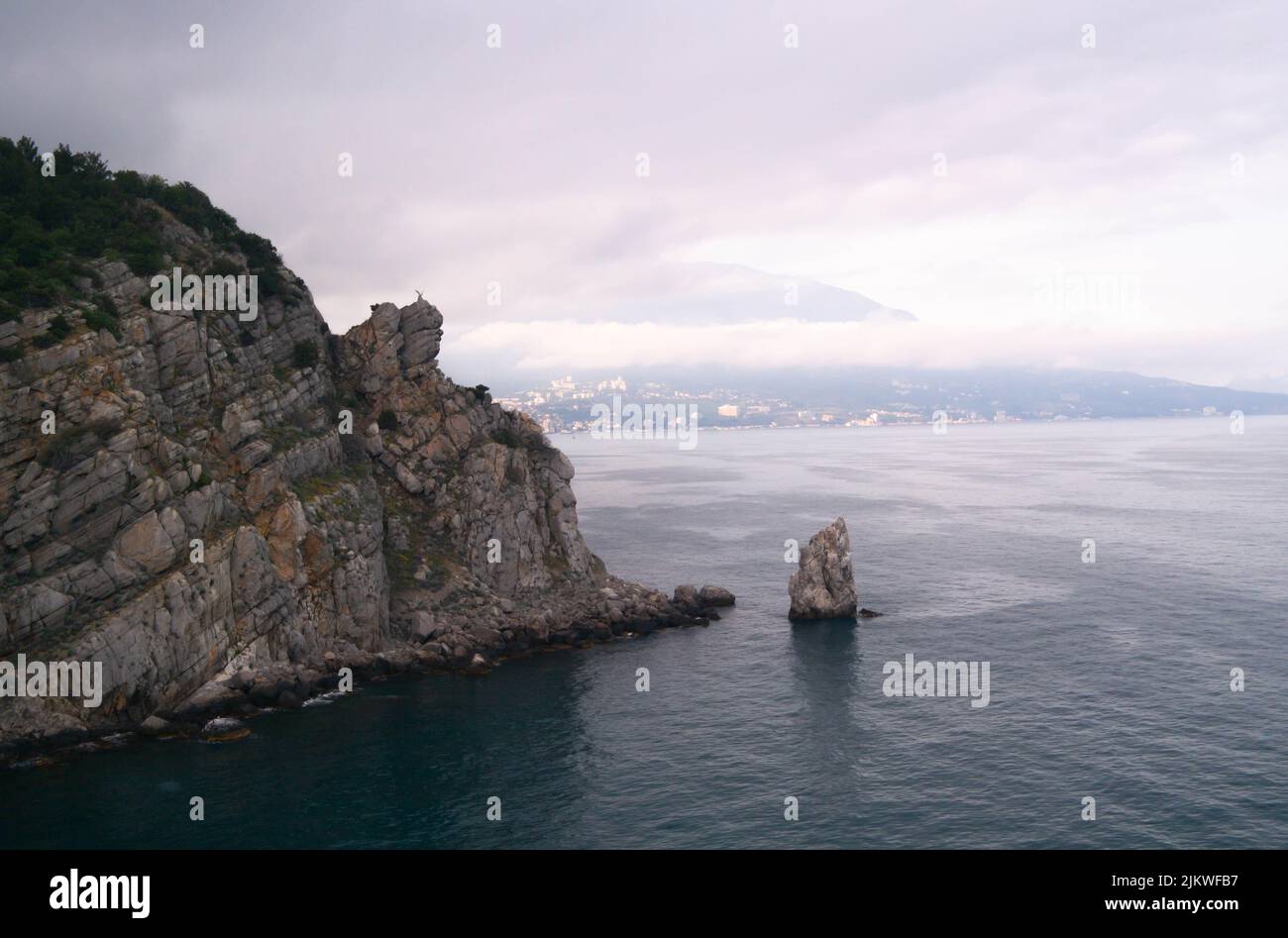 Ein Felsen im Meer mit einem Adler auf der Oberseite und einem segelförmigen Felsen am Fuß. Stockfoto