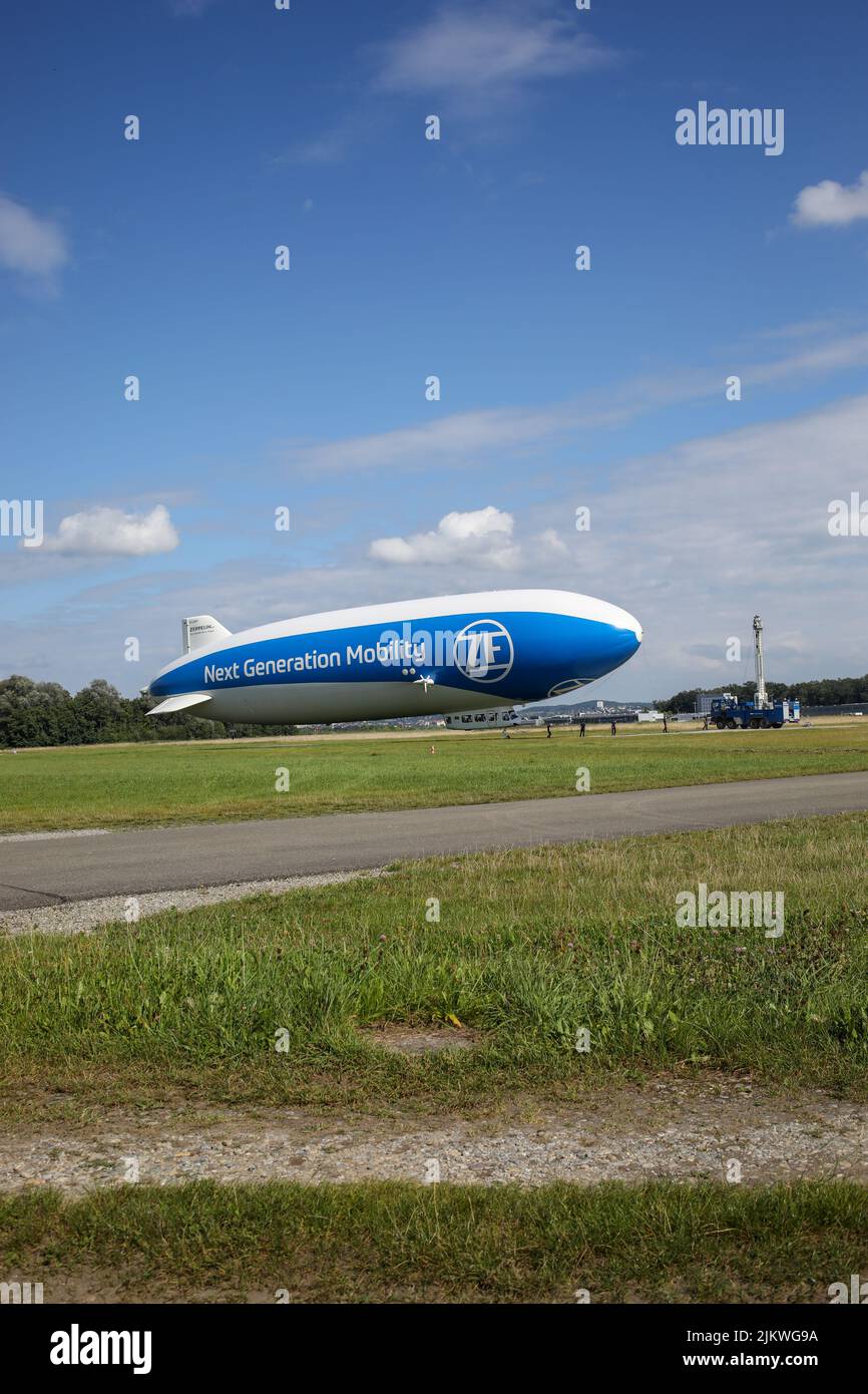Eine vertikale Aufnahme eines Zeppelin-Hangars, der tagsüber in der Nähe eines Feldes geparkt hat. Stockfoto
