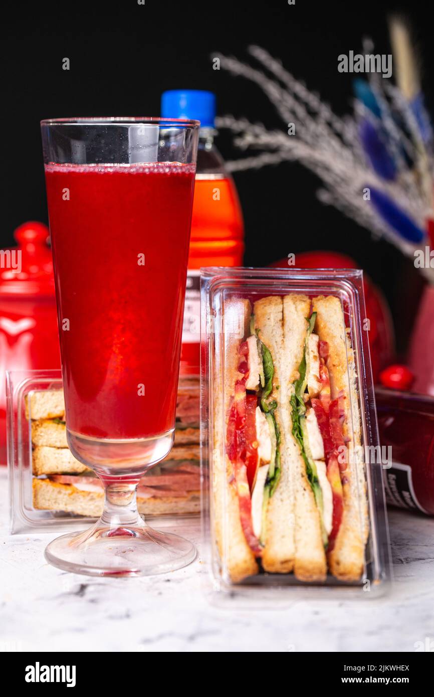 Sandwich mit Füllung in Kunststoffverpackung. Schneller Snack mit einem Getränk. Stockfoto