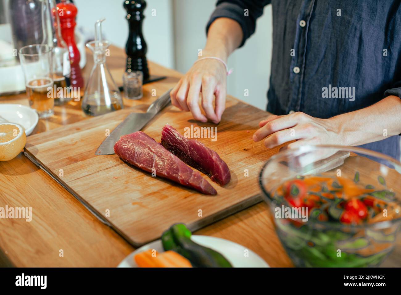 Eine Nahaufnahme des Mannes, der Fleisch auf dem Holzbrett in der Küche geschnitten hat. Kochkonzept. Stockfoto