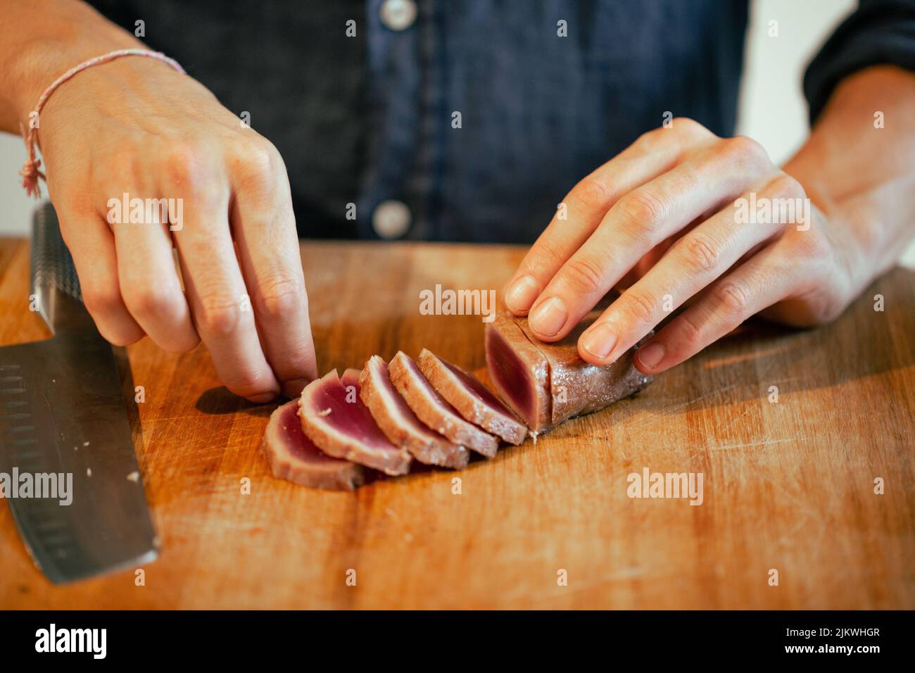 Eine Nahaufnahme des Mannes, der Fleisch auf dem Holzbrett in der Küche geschnitten hat. Kochkonzept. Stockfoto
