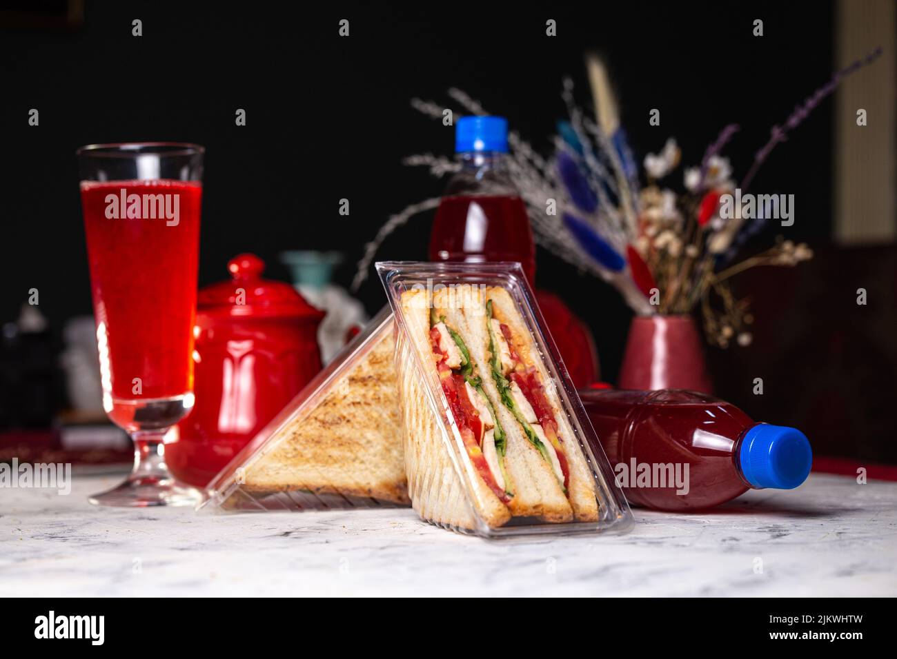 Sandwich mit Füllung in einer Plastikverpackung und einem Getränk in einer Flasche. Stockfoto