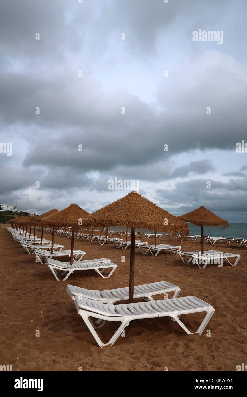 Eine Reihe von Strandliegen an einem leeren Strandresort in Südeuropa an einem bewölkten Tag ohne Touristen. Stockfoto