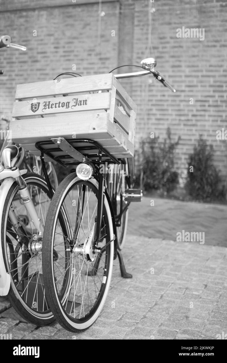 Eine vertikale Graustufenaufnahme eines niederländischen Fahrrads mit Holzkiste auf dem vorderen Gepäckträger Stockfoto