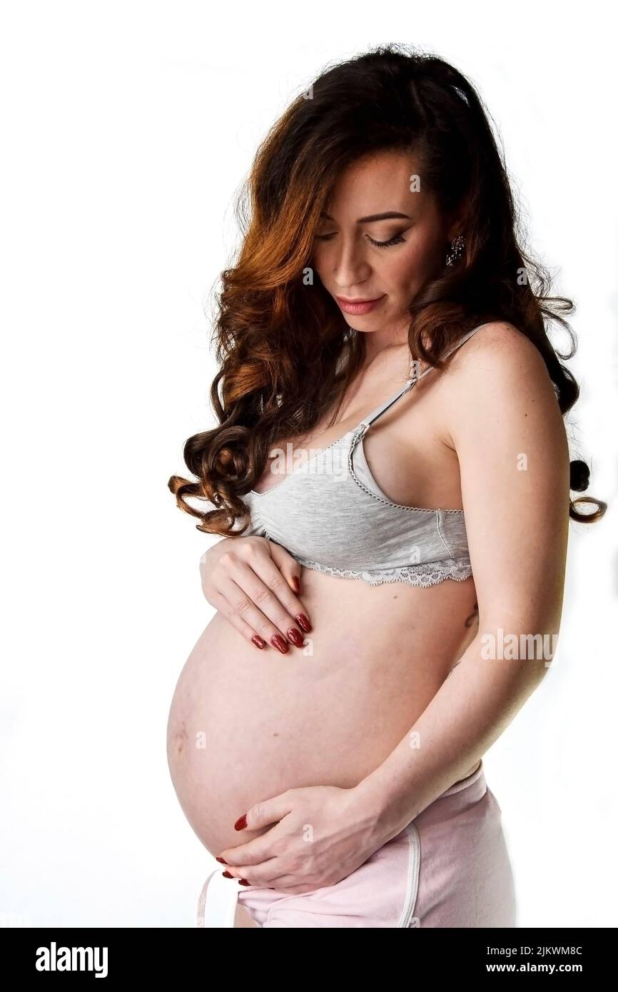Eine vertikale Aufnahme einer schönen Schwangeren mit den Händen über ihrem Bauch auf weißem Hintergrund Stockfoto
