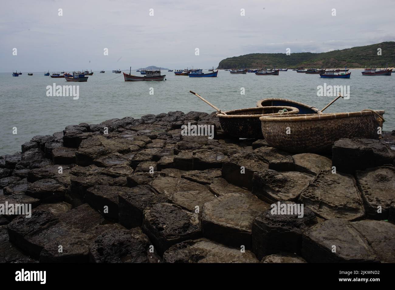 Drei vietnamesische runde Fischerboote an der Küste des Meeres mit einem Hafen Stockfoto