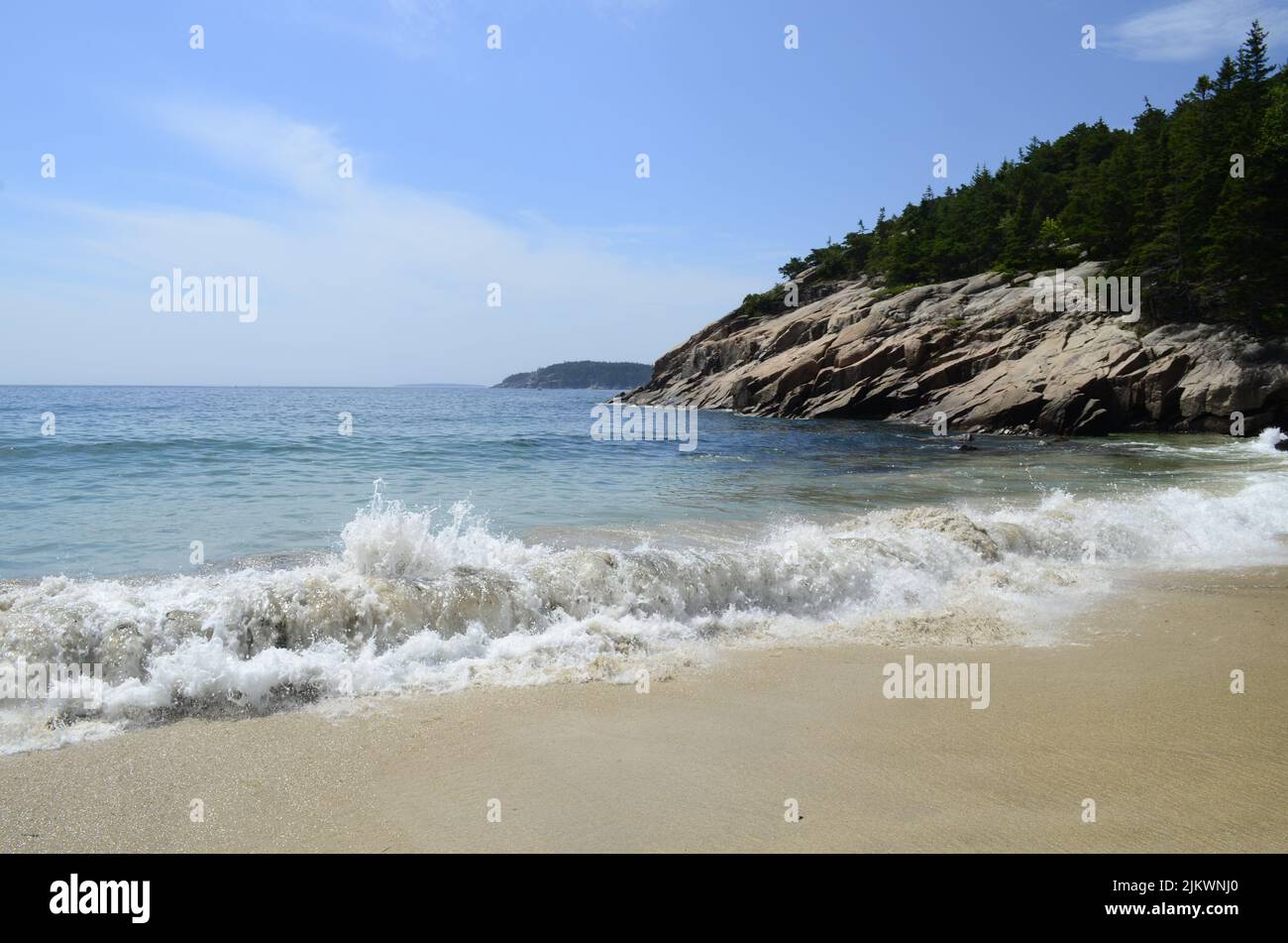 Im Sommer schwammen schäumende Wellen ruhig am Sandstrand Stockfoto