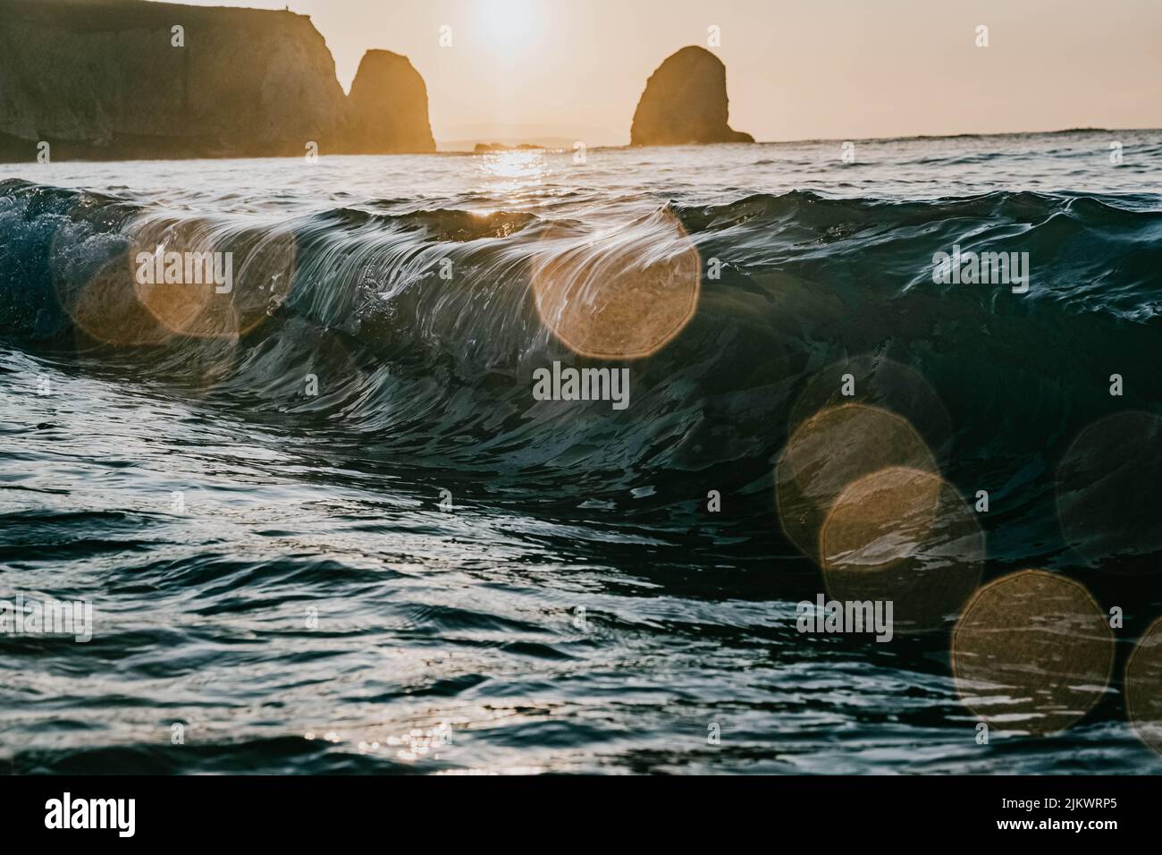 Nahaufnahme einer Meereswelle gegen eine helle Sonne mit Bokeh-Effekt Stockfoto