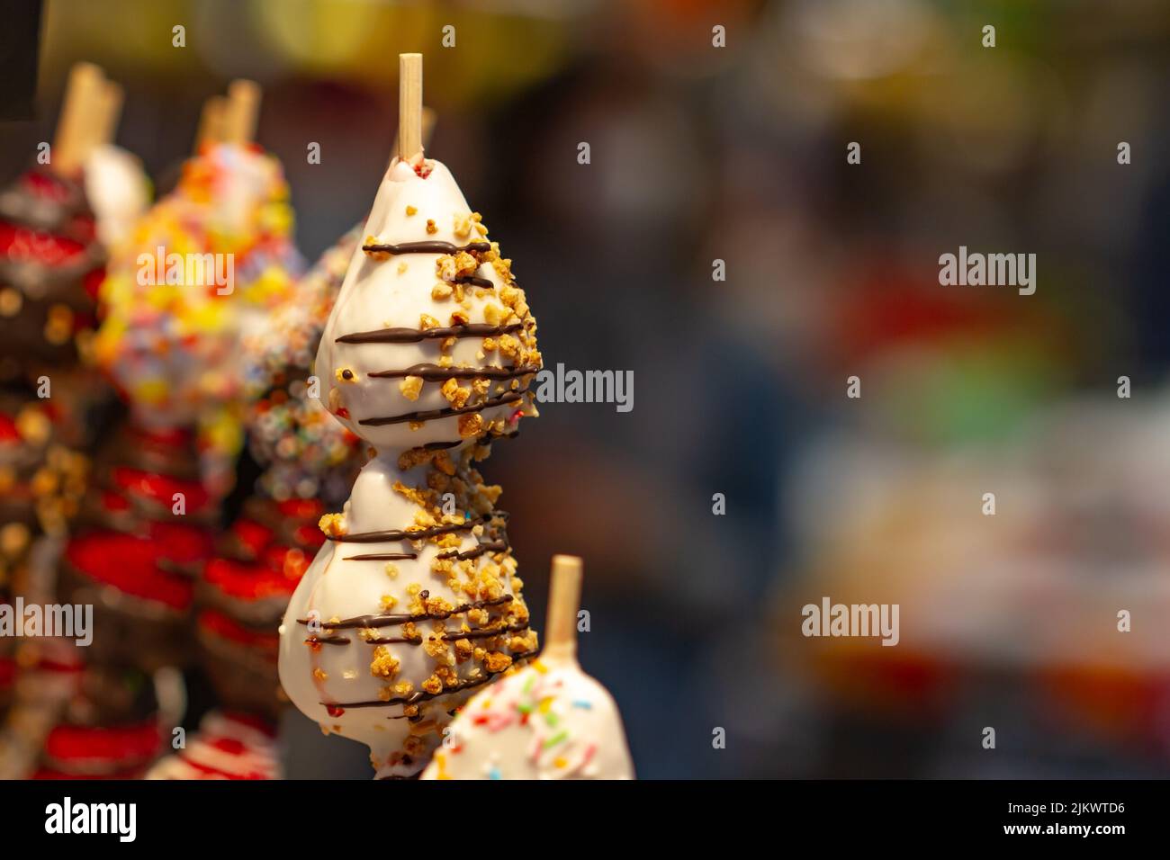 Erdbeere bedeckt mit weißer Schokolade und bedeckt mit Nüssen auf Spießen auf dem Boqueria Markt in Barcelona (Spanien). Stockfoto