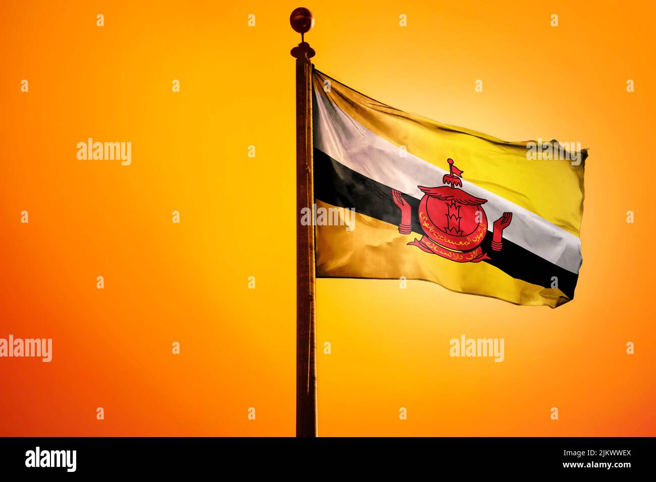 Eine digitale Illustration der Flagge Bruneis, die gegen einen leuchtend gelben Himmel schwenkt Stockfoto