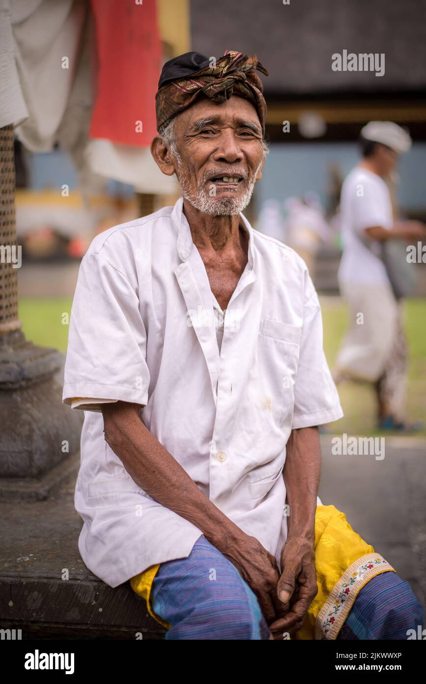 Eine vertikale Aufnahme eines alten Mannes am Pura Bratan Tempel auf einem See in Bali, Indonesien Stockfoto