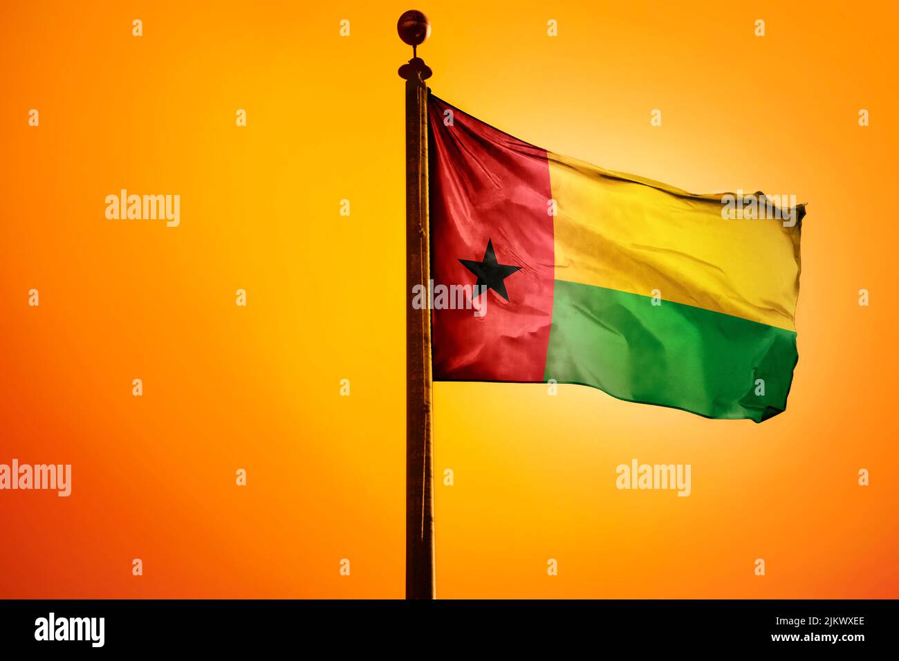 Die Nationalflagge von Guinea-Bissau auf einem Fahnenmast isoliert auf einem orangen Hintergrund Stockfoto