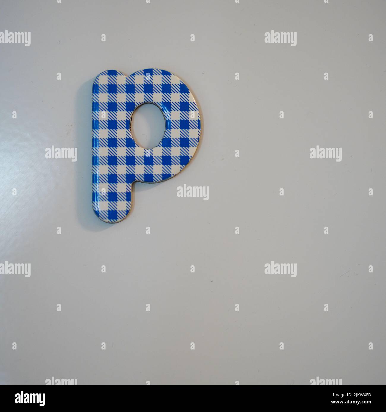 Ein kleingeschriebter Buchstabe 'r' aus Karton mit einem Gingham-Muster auf grauem Hintergrund Stockfoto