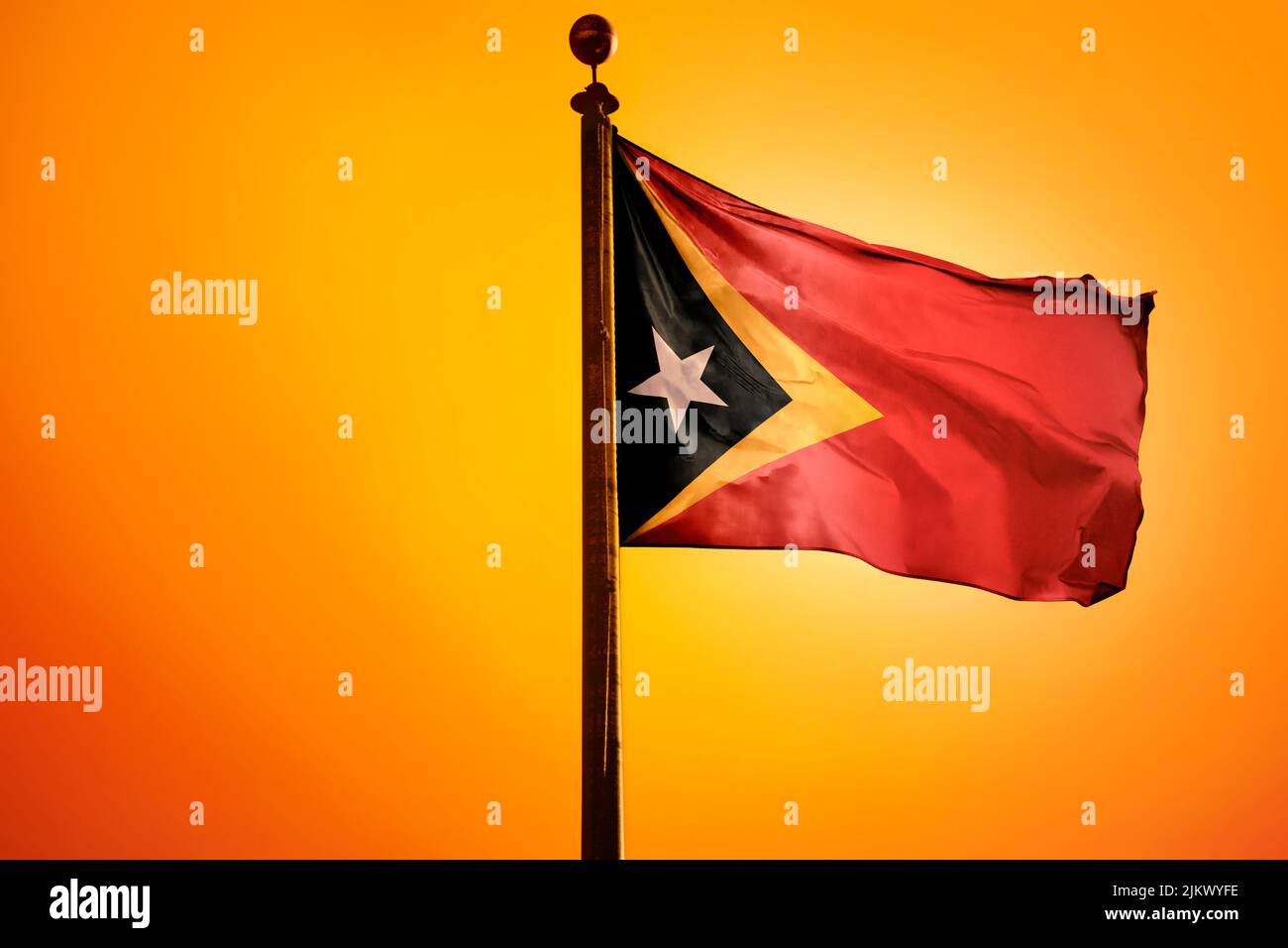 Eine Darstellung der Timor-Leste-Flagge aus dem Jahr 3D, die im Wind winkt, mit orangefarbenem Hintergrund Stockfoto
