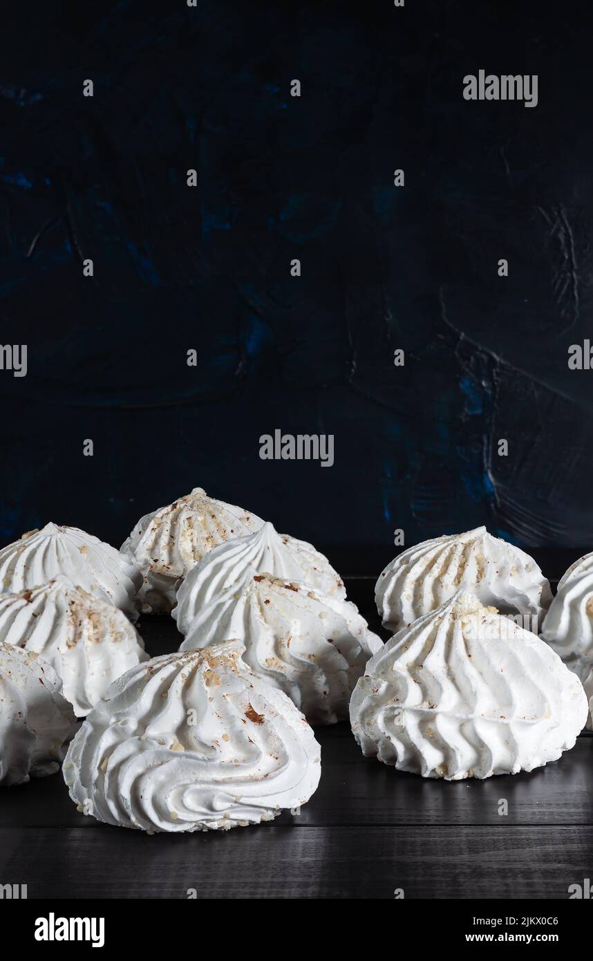 Nahaufnahme einer Gruppe französischer Meringues mit Nüssen, die aus mit Zucker gepeitschten und gebackenen Eiern auf einem dunklen Holztisch mit Platz zum Kopieren zubereitet werden Stockfoto