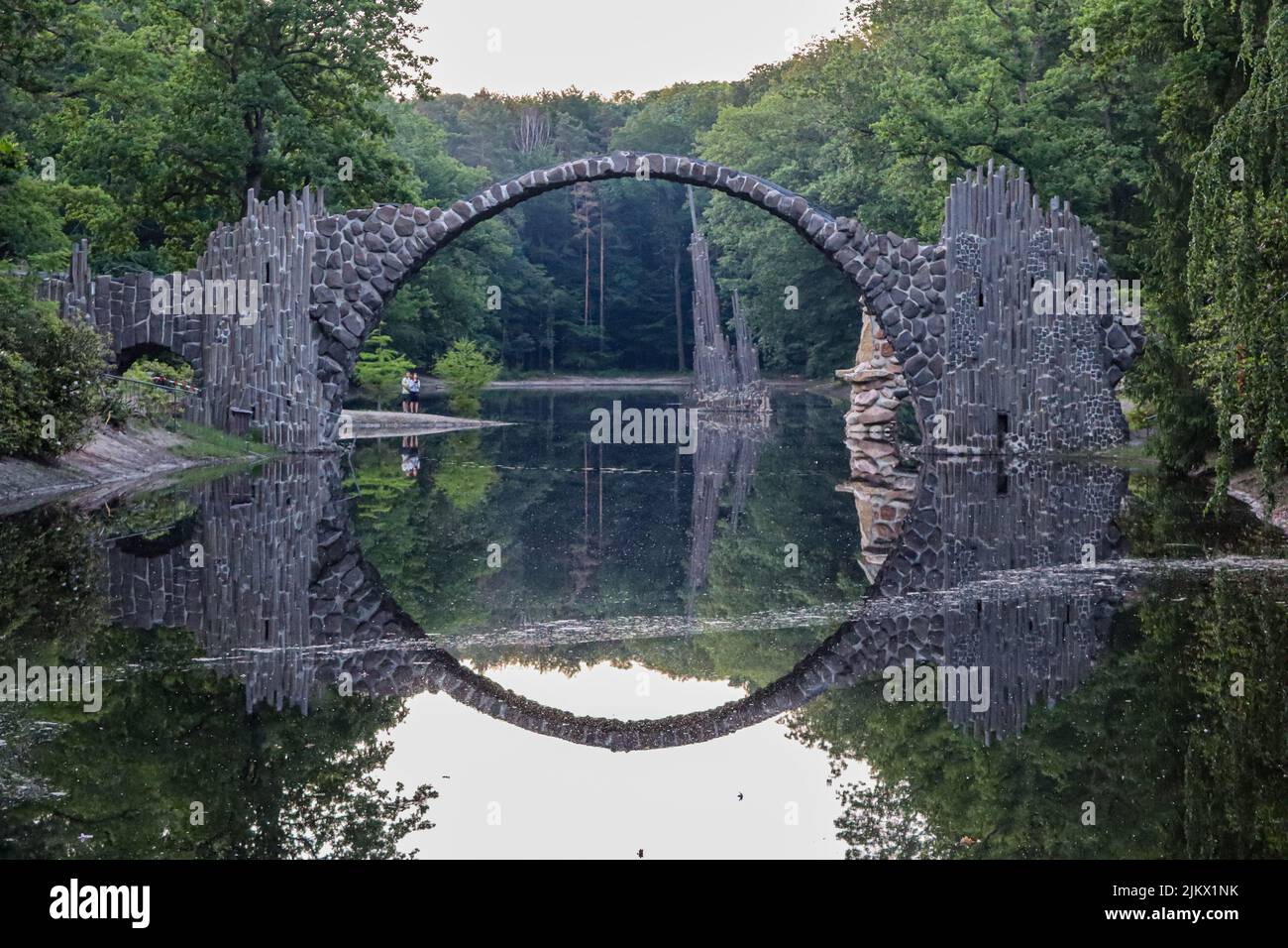 Eine Spiegelung einer Brücke und Bäume in ruhigem Wasser Stockfoto