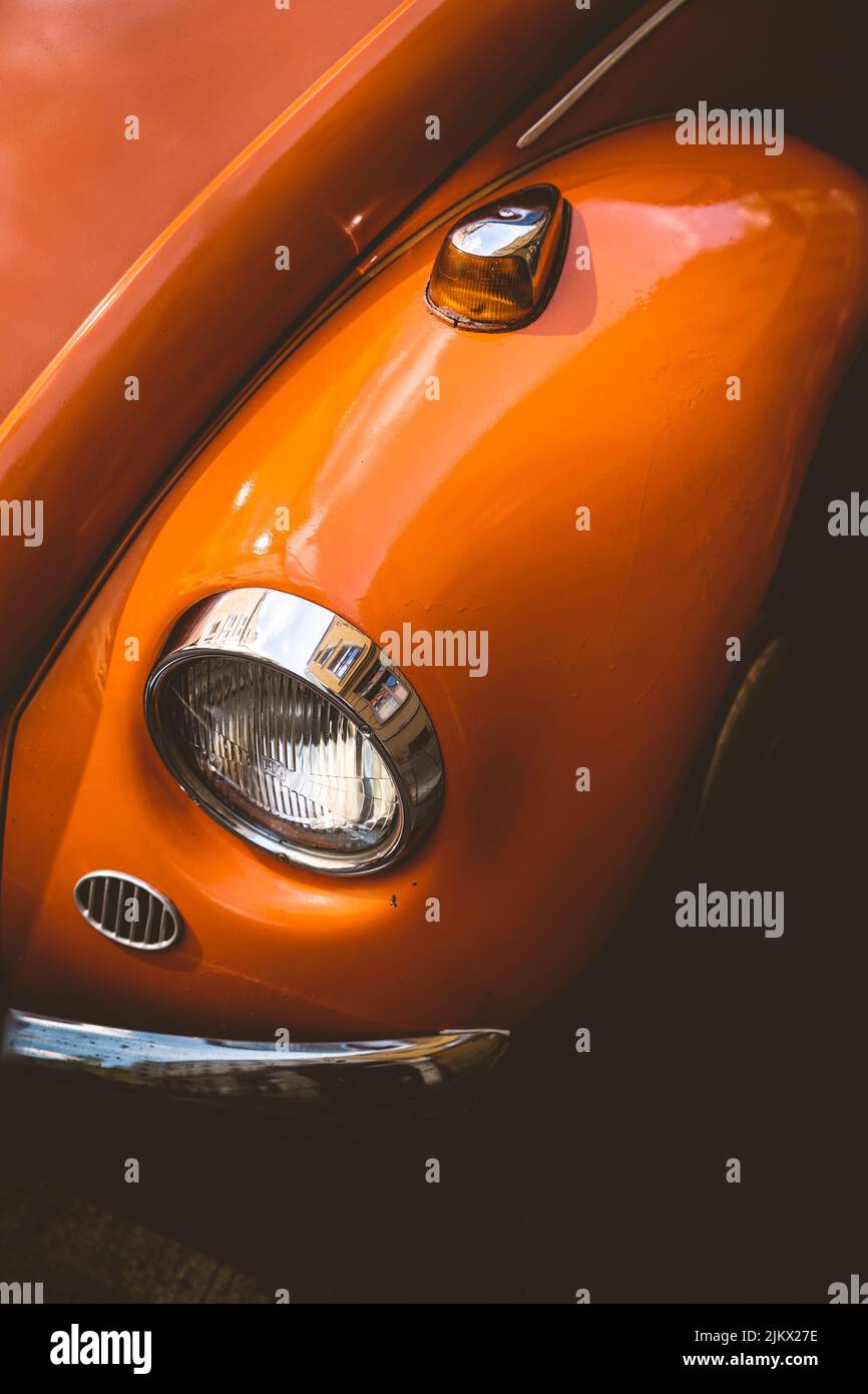 Historischer Oldtimer VW Käfer mit oranger Farbe. Der Oldtimer befindet sich in der Innenstadt von München und passt gut in die historische Landschaft Stockfoto