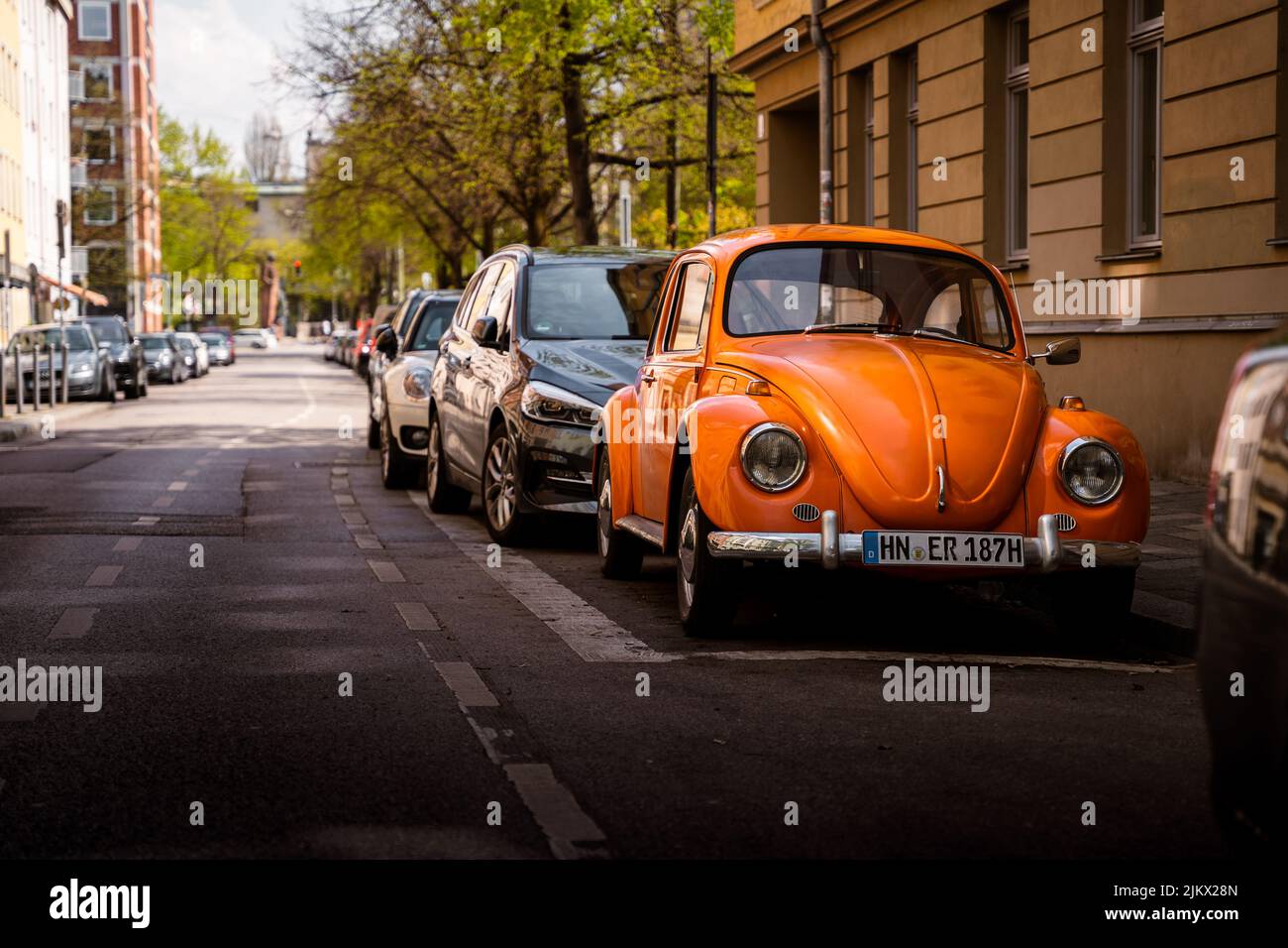 Historischer Oldtimer VW Käfer mit oranger Farbe. Der Oldtimer befindet sich in der Innenstadt von München und passt gut in die historische Landschaft Stockfoto