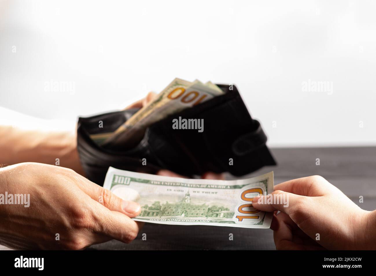 US-Geld in Ledertasche auf weißem Hintergrund in Unschärfe. Vatertag, selektiver Fokus. Der Mann zählt Geld in der Hand. Wirtschaft, Sparen, Gehalt und d Stockfoto