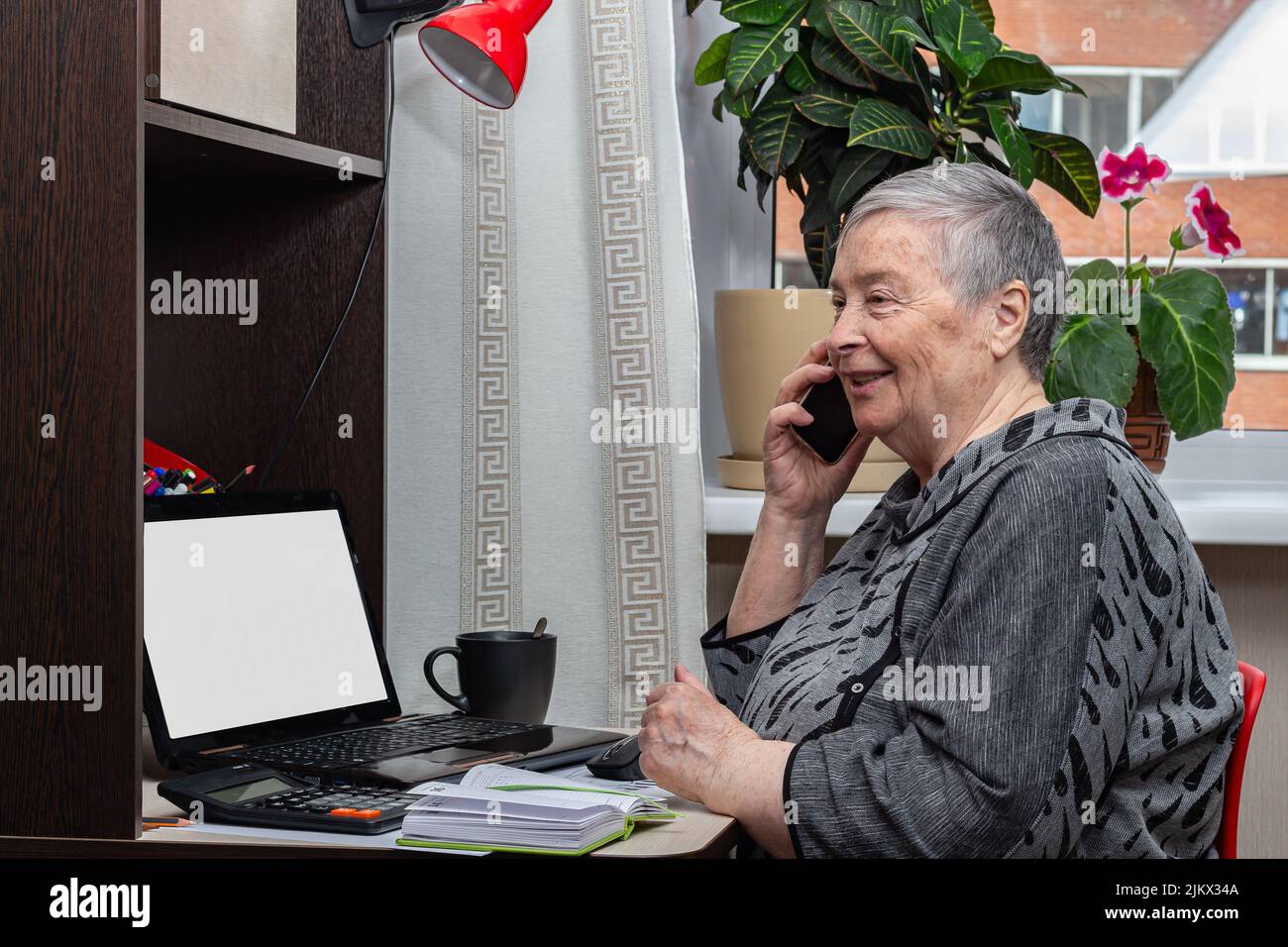 Charmante ältere Frau lächelt am Telefon zu Hause sprechen. Mit Technologie, Großeltern Tag, glücklich und erfolgreich im Ruhestand Leben. Selektiver Fokus Stockfoto