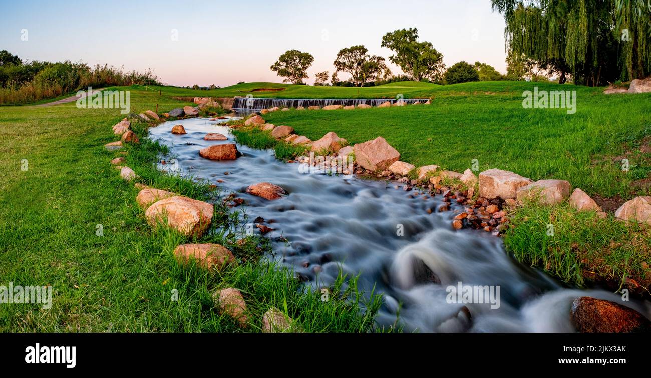 Eine natürliche Landschaft Blick auf einen Fluss fließt in der grünen unberührten Feld Stockfoto