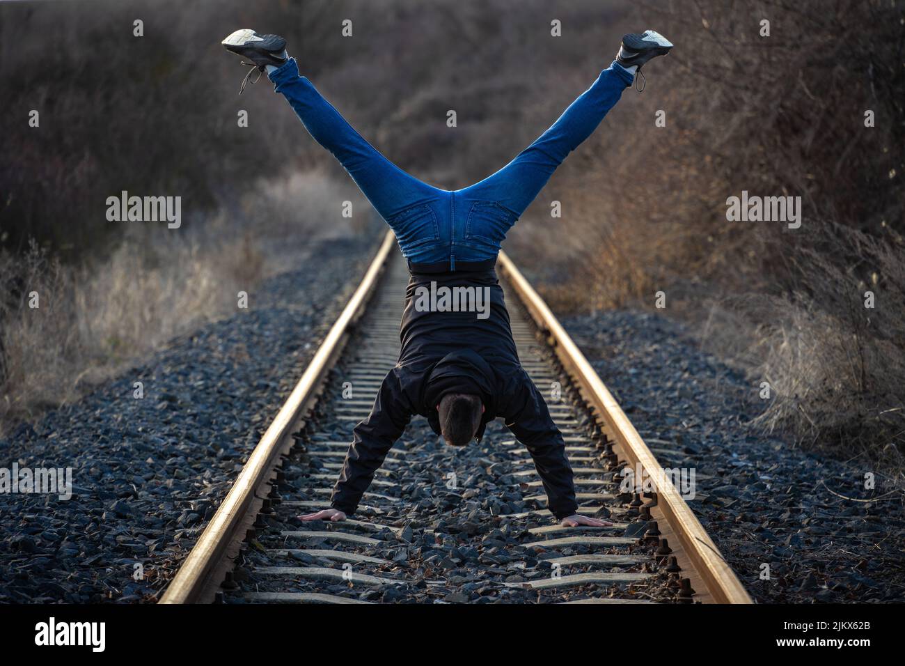 Ein junger Mann macht einen Handstand auf einer Eisenbahnstrecke Stockfoto