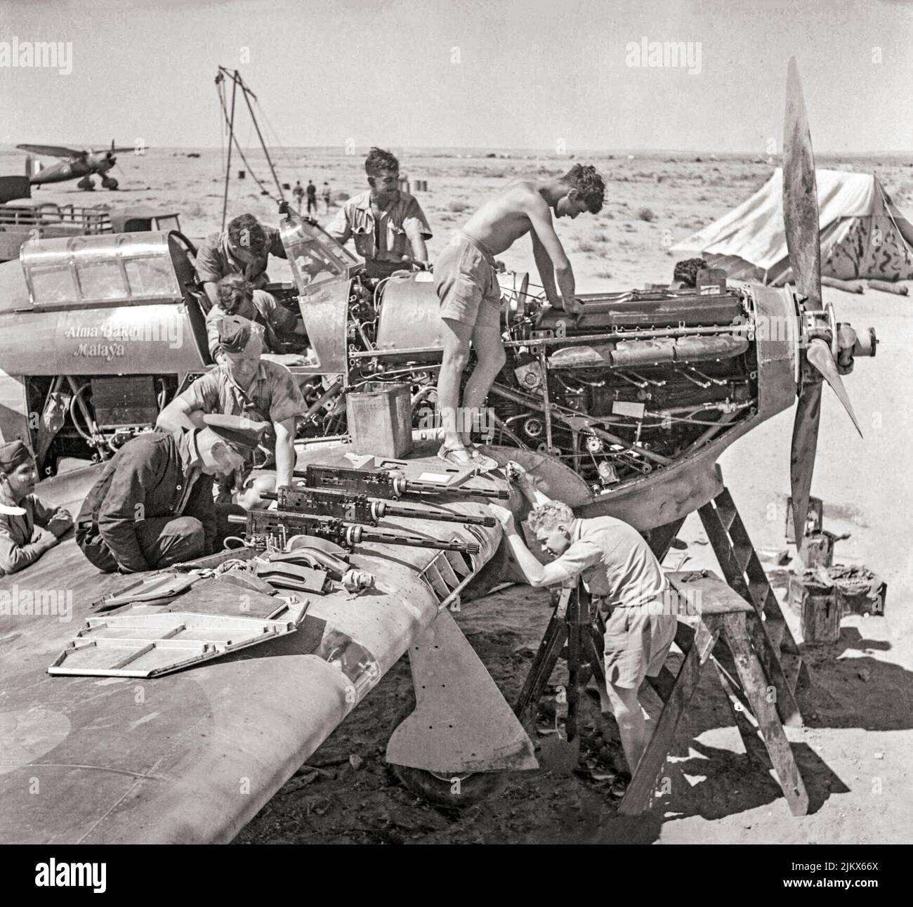 Die Bodenbesatzung der RAF-Staffel Nr. 274 überholung einen Hawker-Orkan Mark I in Libyen während der Verteidigung von Tobruk. Die britischen Einsitzer-Kampfflugzeuge kämpften in allen großen Theatern des Zweiten Weltkriegs. Im Hintergrund ist eine Westland Lysander STOL zu sehen Stockfoto