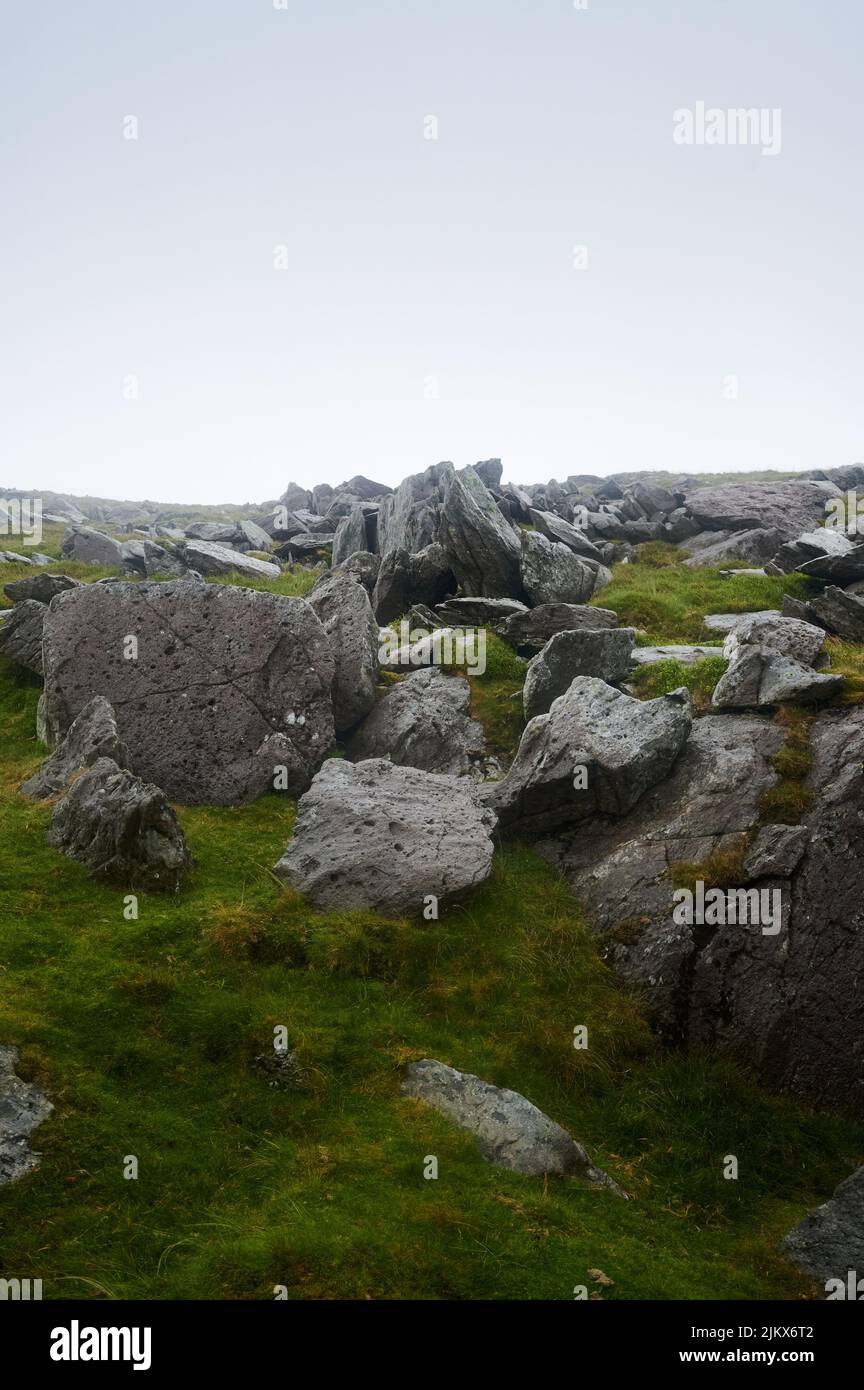 Blick über Felsen und Gras an einem grauen Regentag auf einem Hügel in wales, Großbritannien Stockfoto