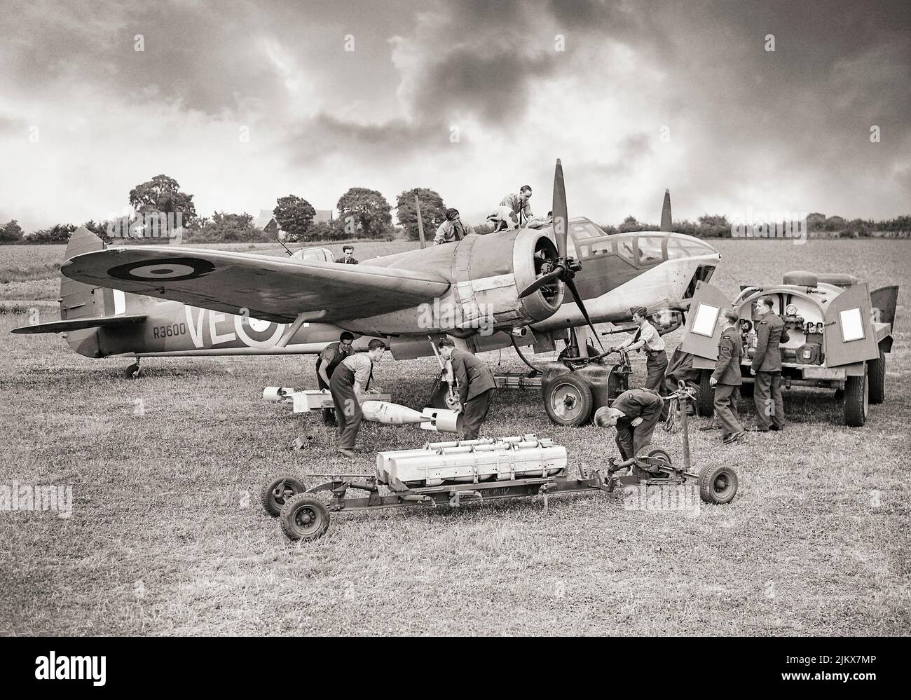 Ein Bristol Blenheim Mark IV, der Nr. 110 Squadron RAF, wird bei RAF Wattisham, Suffolk, England, aufwendig gewartet. Die Waffenschmiede entlädt GP-Bomben und Kleinbombenbehälter (SBCs) mit Brandsätzen von 250 kg aus einem Wagen, während andere Bodenbesatzungen das Flugzeug auftanken und sich um die Motoren, das Cockpit und den Geschützturm kümmern. Den Hund auf der Motorverkleidung notieren. Stockfoto