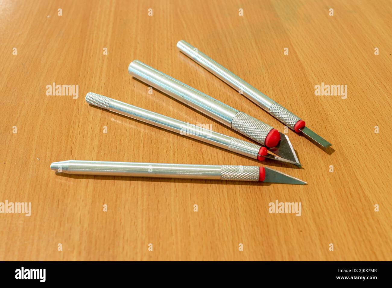 Verschiedene scharfe Präzisionsmesser mit verschiedenen Klingen auf einer lackierten Holzoberfläche Stockfoto